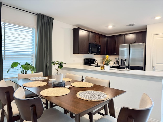 kitchen featuring kitchen peninsula, dark brown cabinetry, sink, and black appliances