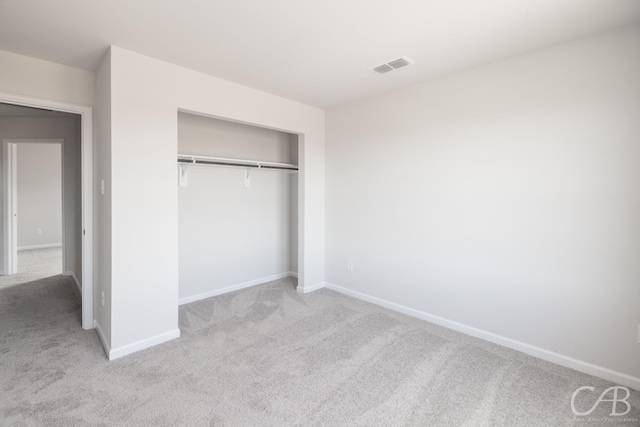 unfurnished bedroom featuring a closet and light carpet