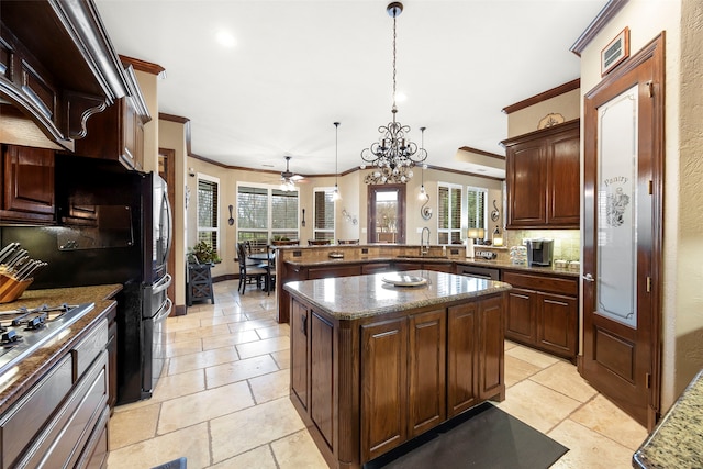 kitchen with pendant lighting, a center island, ceiling fan with notable chandelier, ornamental molding, and kitchen peninsula