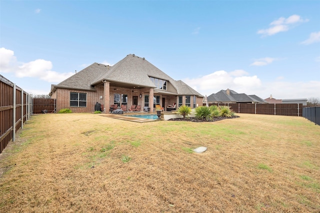 rear view of property featuring a lawn, a patio area, and a fenced in pool