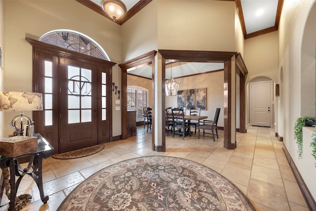 entryway featuring a chandelier, a high ceiling, and crown molding