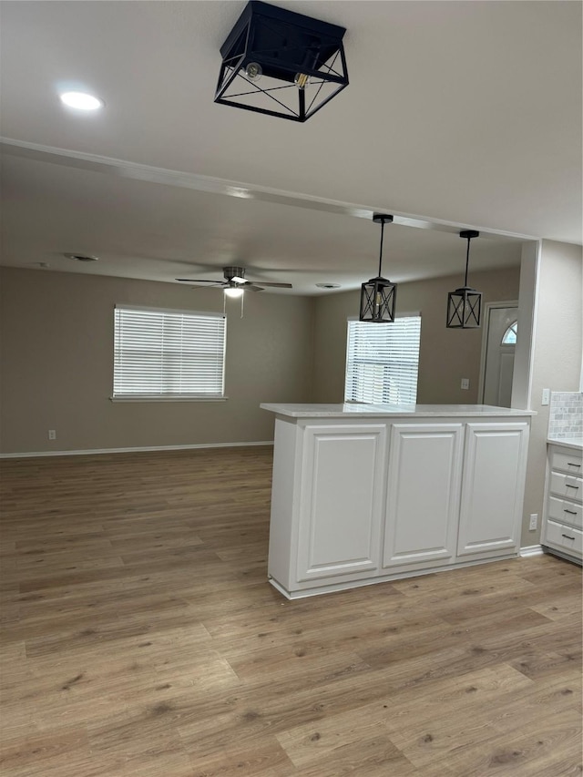 kitchen with white cabinets, light hardwood / wood-style flooring, hanging light fixtures, and ceiling fan