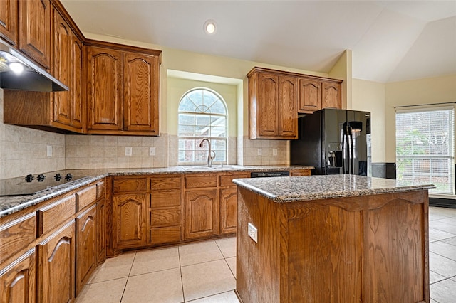 kitchen with decorative backsplash, vaulted ceiling, sink, black appliances, and a kitchen island