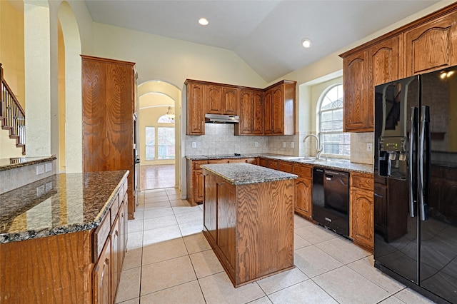 kitchen featuring tasteful backsplash, dark stone countertops, a kitchen island, and black appliances