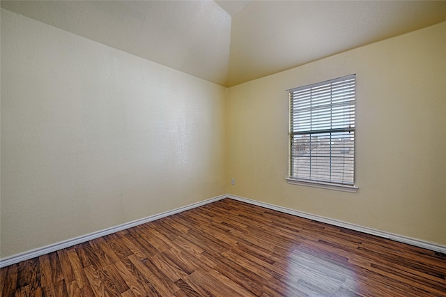 unfurnished room featuring vaulted ceiling and dark wood-type flooring