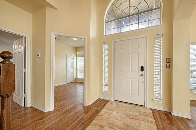 entryway with light wood-type flooring and a towering ceiling