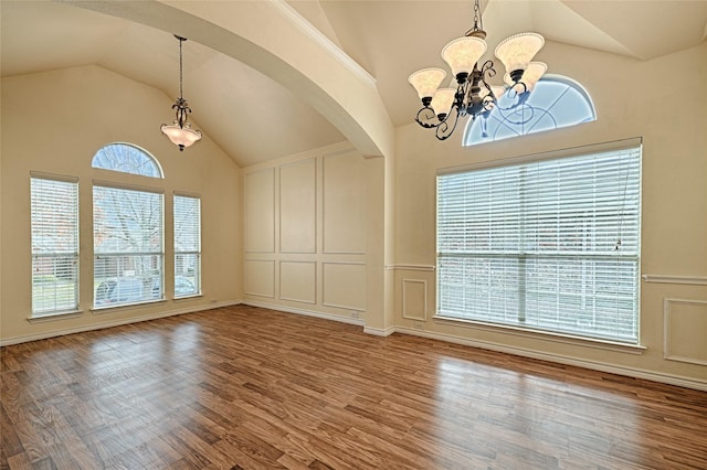 unfurnished dining area with hardwood / wood-style flooring, vaulted ceiling, and an inviting chandelier