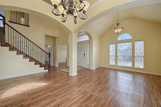 foyer with plenty of natural light, wood-type flooring, a high ceiling, and an inviting chandelier