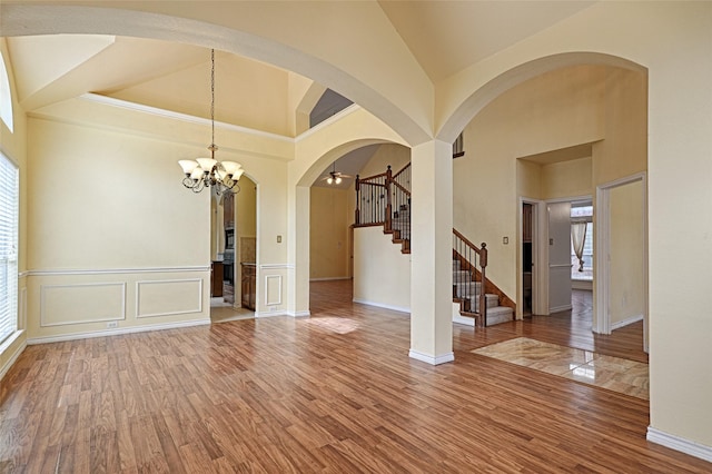 empty room with hardwood / wood-style floors, a notable chandelier, and high vaulted ceiling