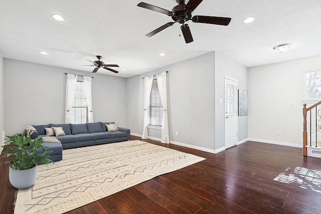 living room featuring a textured ceiling, ceiling fan, and dark wood-type flooring