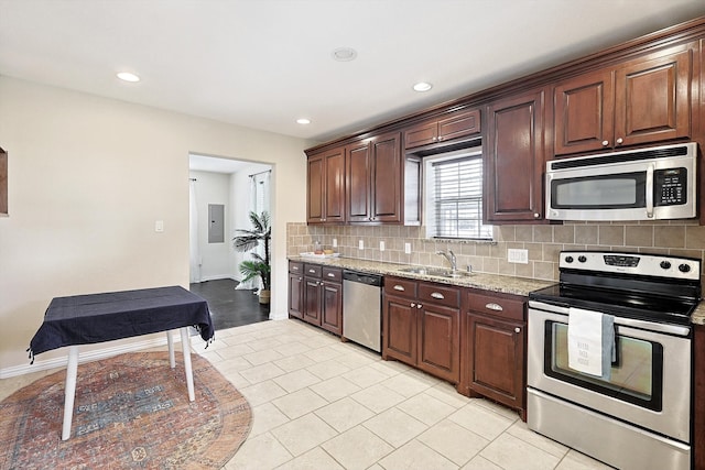 kitchen featuring sink, light stone countertops, appliances with stainless steel finishes, tasteful backsplash, and light tile patterned flooring