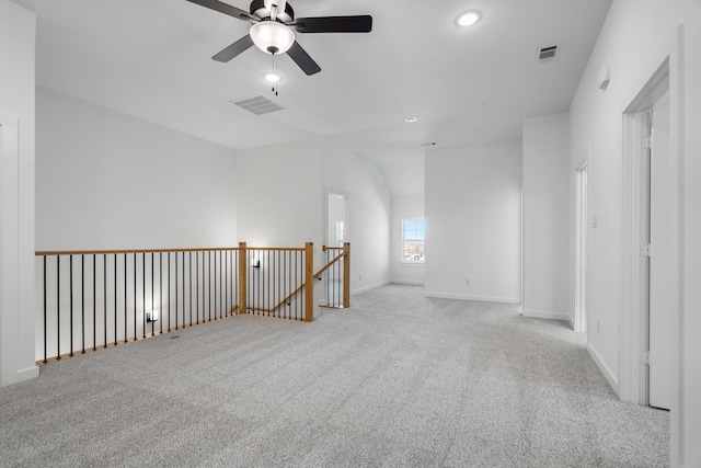 carpeted spare room with ceiling fan and vaulted ceiling