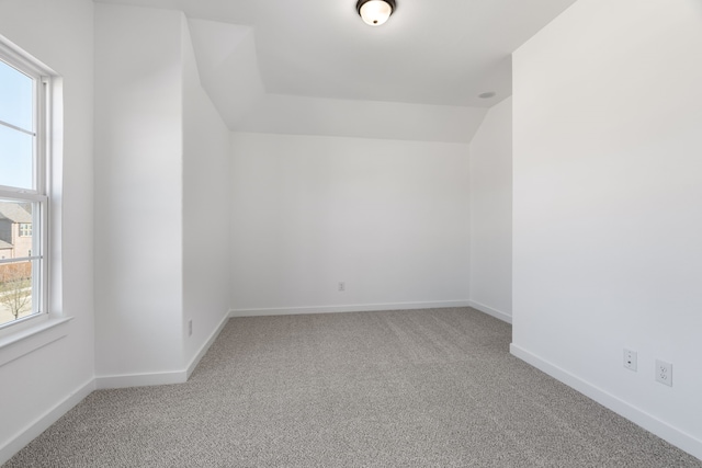 carpeted spare room featuring vaulted ceiling