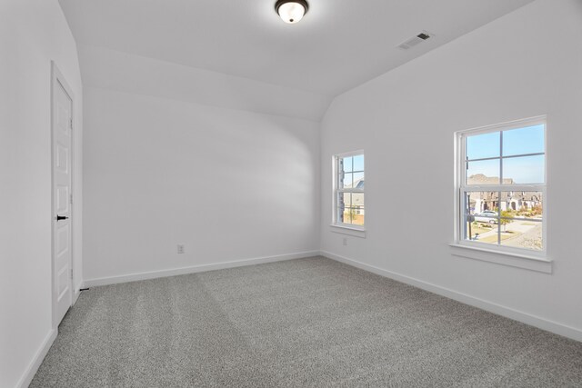 carpeted empty room with lofted ceiling