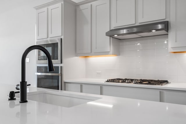 kitchen with white cabinetry, decorative backsplash, sink, and stainless steel appliances