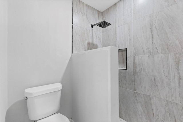 bathroom featuring a tile shower and toilet