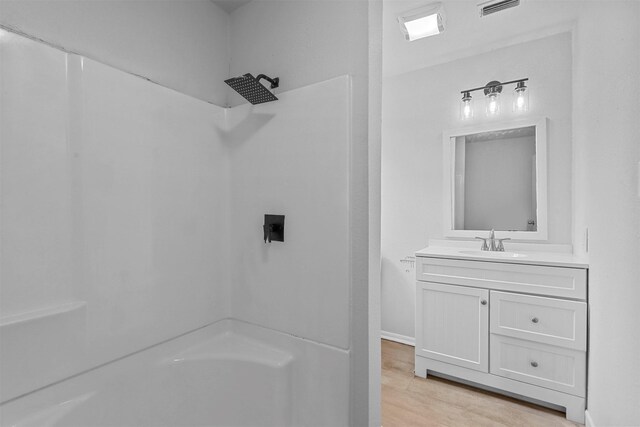 bathroom featuring hardwood / wood-style floors, vanity, and walk in shower