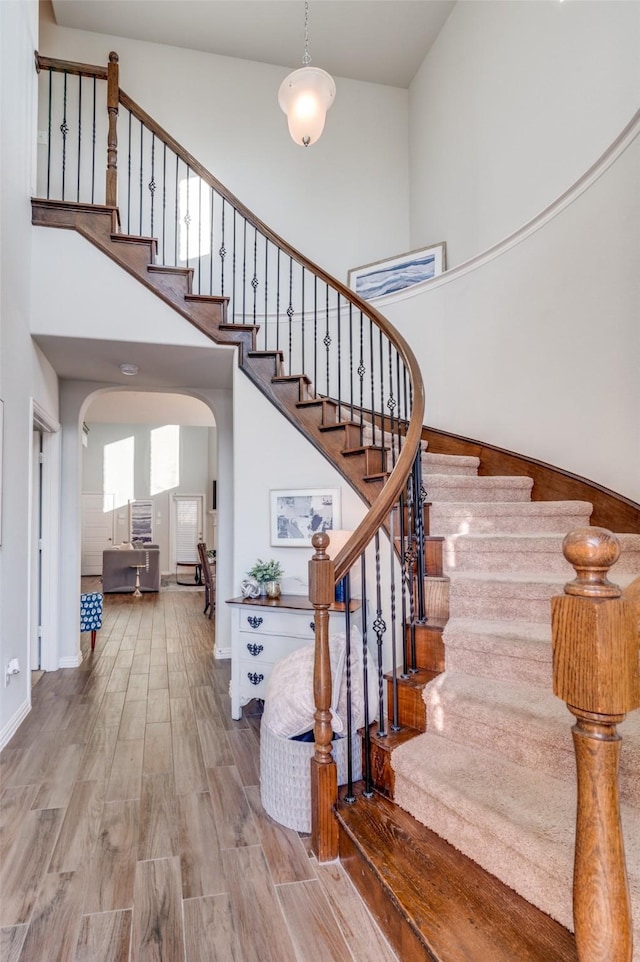 staircase featuring a high ceiling and hardwood / wood-style flooring