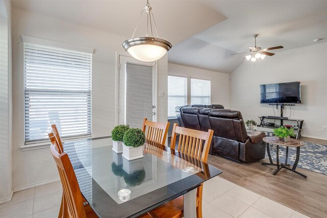 dining area with ceiling fan, light tile patterned floors, and vaulted ceiling