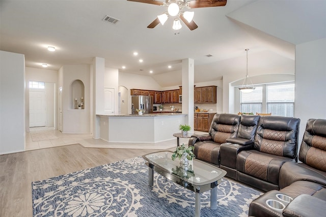 living room featuring vaulted ceiling, light hardwood / wood-style flooring, and ceiling fan