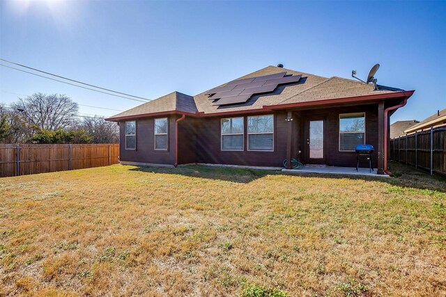 rear view of house with a lawn, solar panels, and a patio area