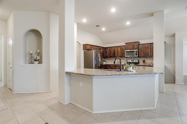 kitchen featuring light stone counters, stainless steel appliances, vaulted ceiling, sink, and light tile patterned floors