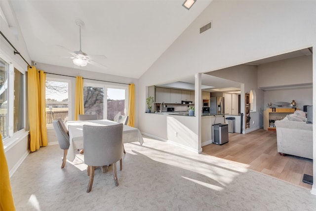 dining space featuring ceiling fan, sink, high vaulted ceiling, and light hardwood / wood-style flooring