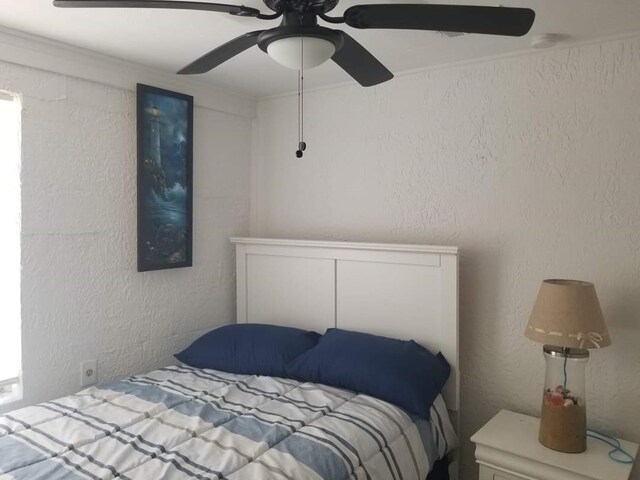 bedroom with ceiling fan and ornamental molding