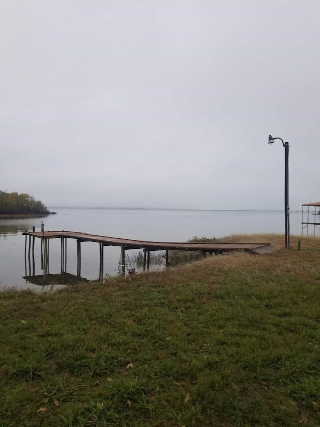 view of dock featuring a water view and a yard