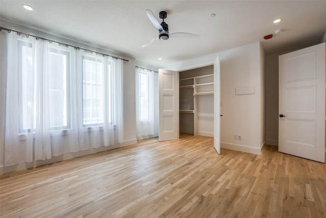 unfurnished bedroom featuring ceiling fan, a closet, and light wood-type flooring