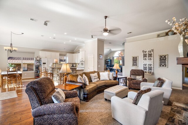 living room featuring ceiling fan with notable chandelier, hardwood / wood-style flooring, vaulted ceiling, and a wealth of natural light