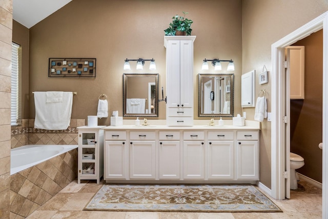 bathroom with a relaxing tiled tub, toilet, and vanity