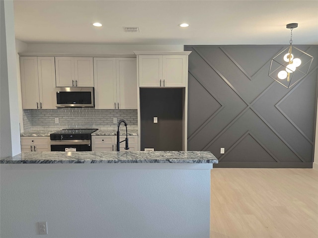 kitchen featuring hanging light fixtures, range with electric cooktop, white cabinets, decorative backsplash, and dark stone counters