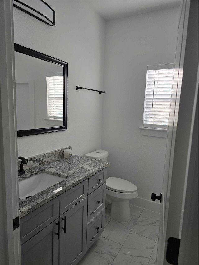 bathroom featuring vanity, toilet, and a healthy amount of sunlight