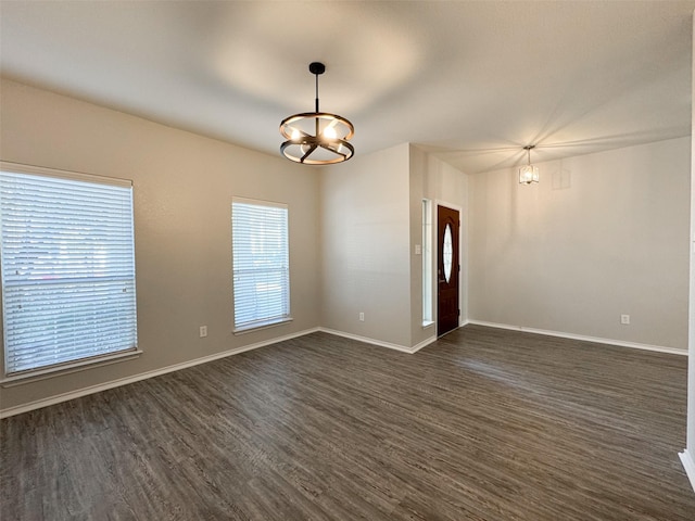 spare room featuring dark hardwood / wood-style flooring and an inviting chandelier