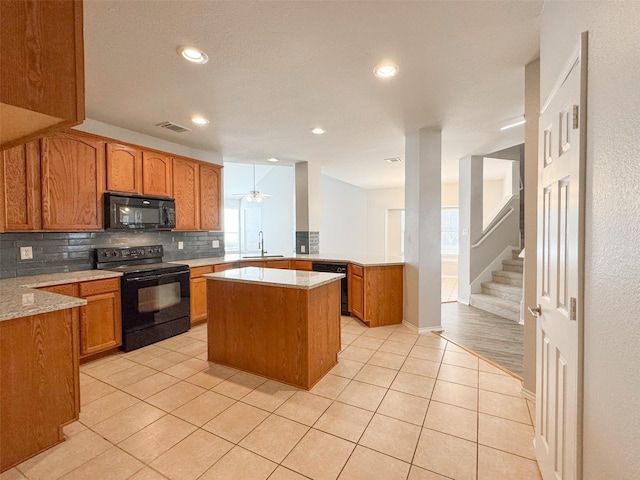 kitchen with a kitchen island, black appliances, sink, light tile patterned floors, and kitchen peninsula