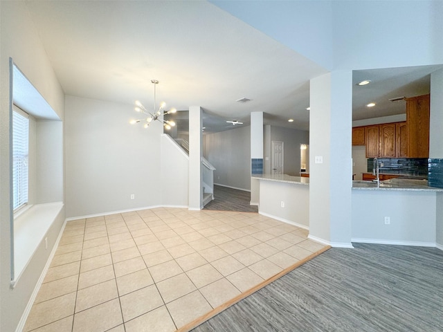 unfurnished living room with sink, light tile patterned floors, and a notable chandelier