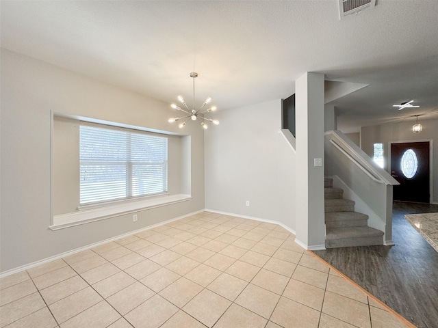 tiled empty room featuring a chandelier