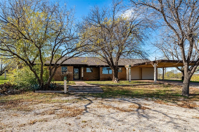 single story home featuring dirt driveway, brick siding, and an attached garage