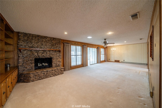 living room with a textured ceiling, light colored carpet, a fireplace, visible vents, and baseboard heating