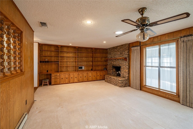 unfurnished living room featuring visible vents, wood walls, light carpet, and a textured ceiling