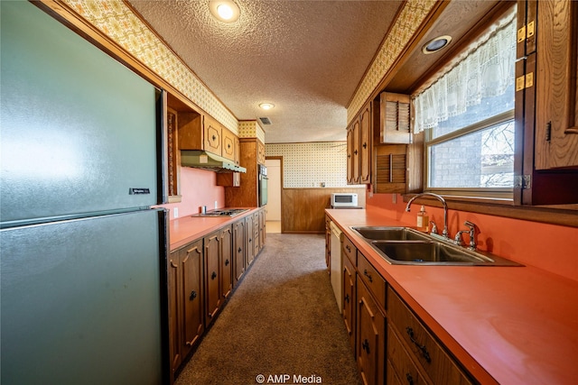 kitchen featuring wallpapered walls, freestanding refrigerator, light countertops, a textured ceiling, and a sink