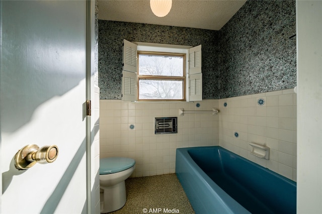 bathroom featuring a wainscoted wall, a garden tub, toilet, and wallpapered walls