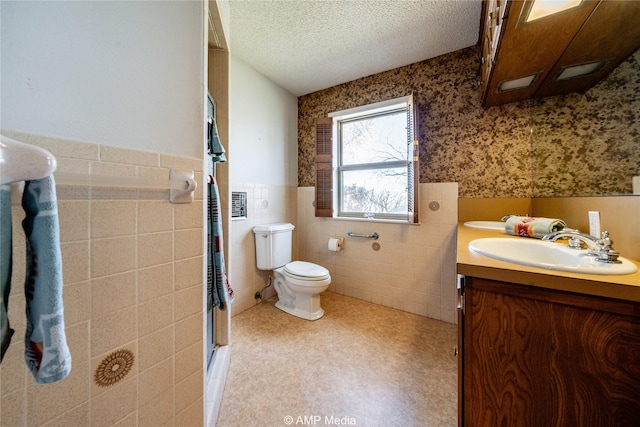 full bath featuring a textured ceiling, toilet, a sink, wainscoting, and double vanity