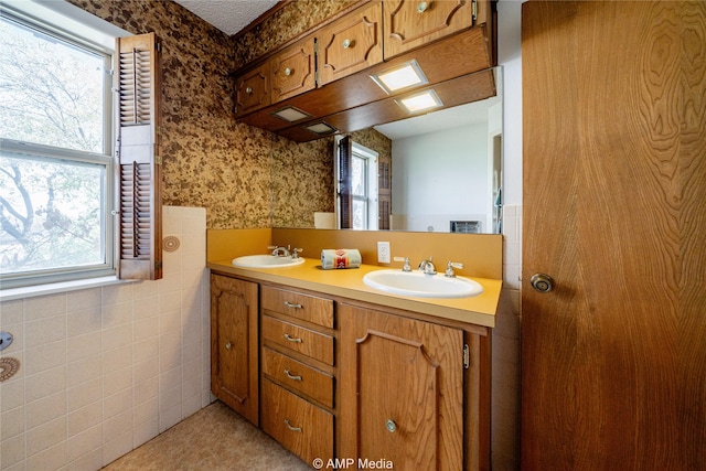 full bath featuring double vanity, a sink, and wallpapered walls