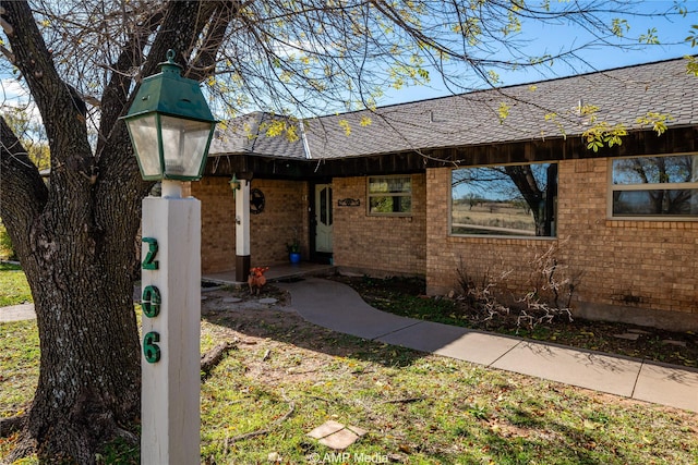 view of front of house with brick siding and roof with shingles