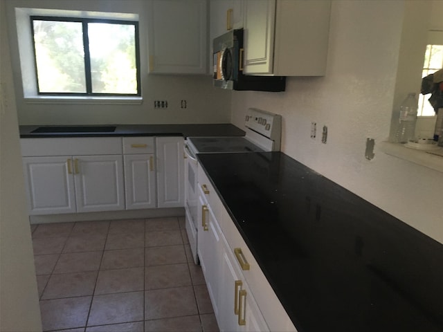 kitchen with dark countertops, white range with electric stovetop, white cabinets, and light tile patterned flooring