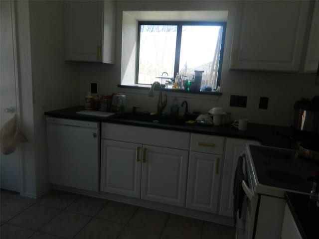 kitchen featuring white appliances, light tile patterned floors, white cabinets, dark countertops, and a sink