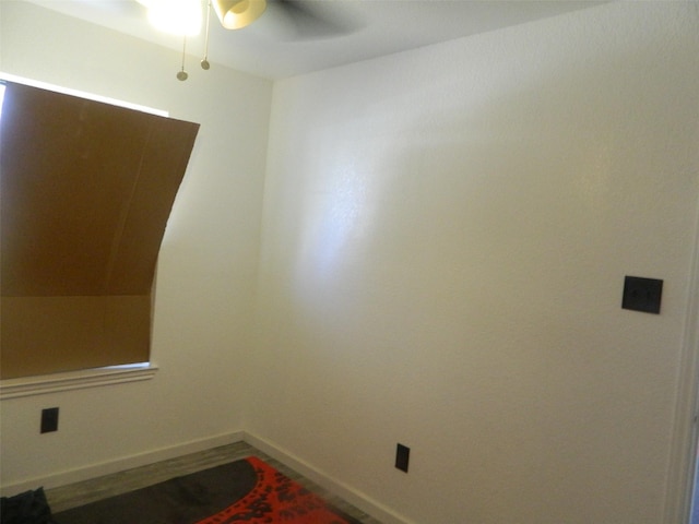 empty room featuring wood finished floors, a ceiling fan, and baseboards