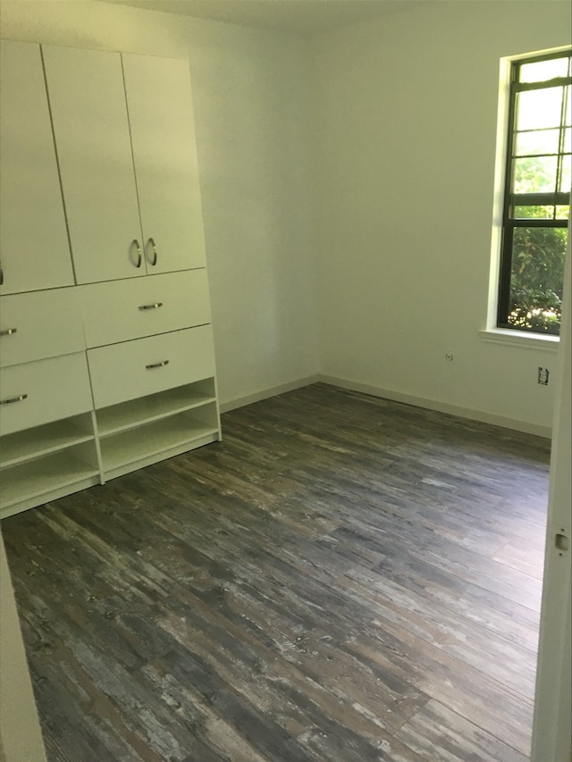 unfurnished bedroom with dark wood-style floors and baseboards